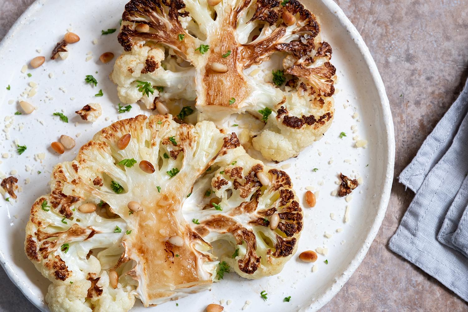 A beautifully plated dish of cauliflower steaks with balsamic reduction and mushrooms