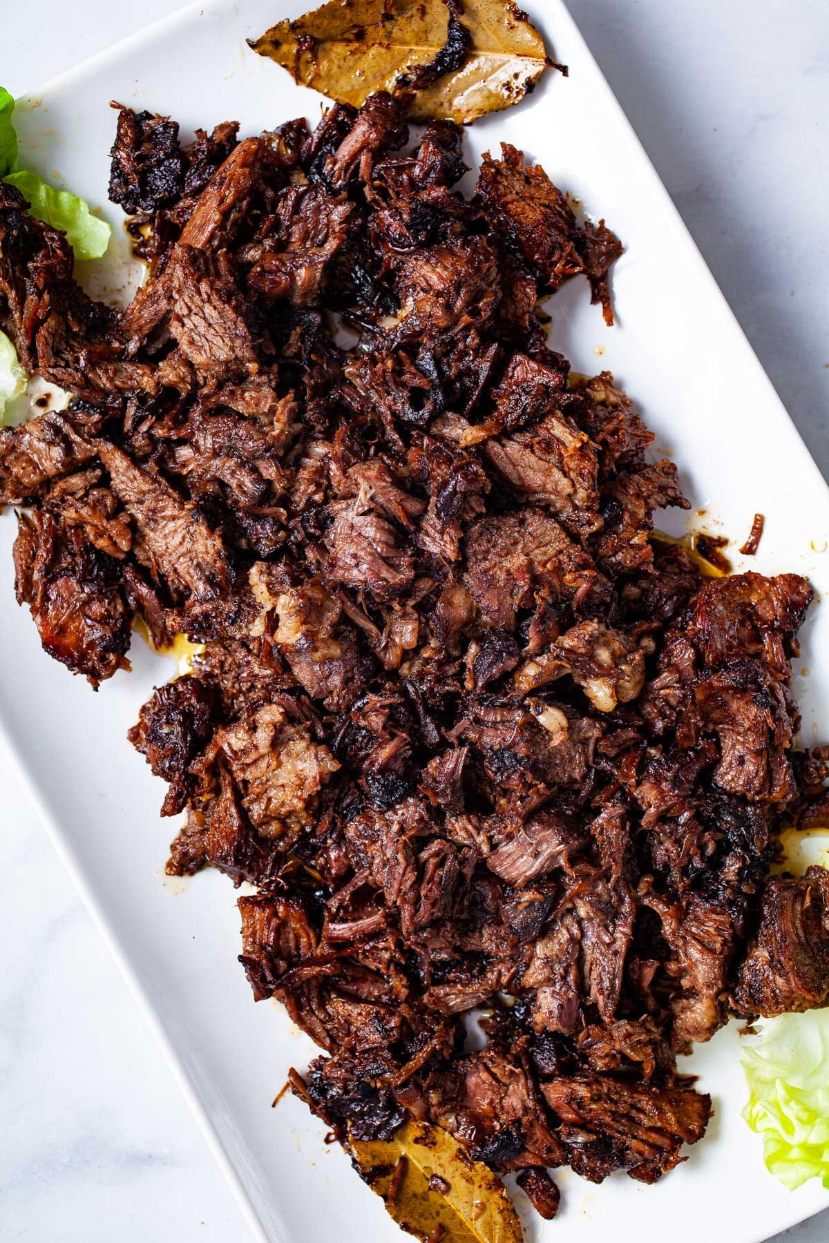 close up of chuck roast being shredded with a fork in a dutch oven