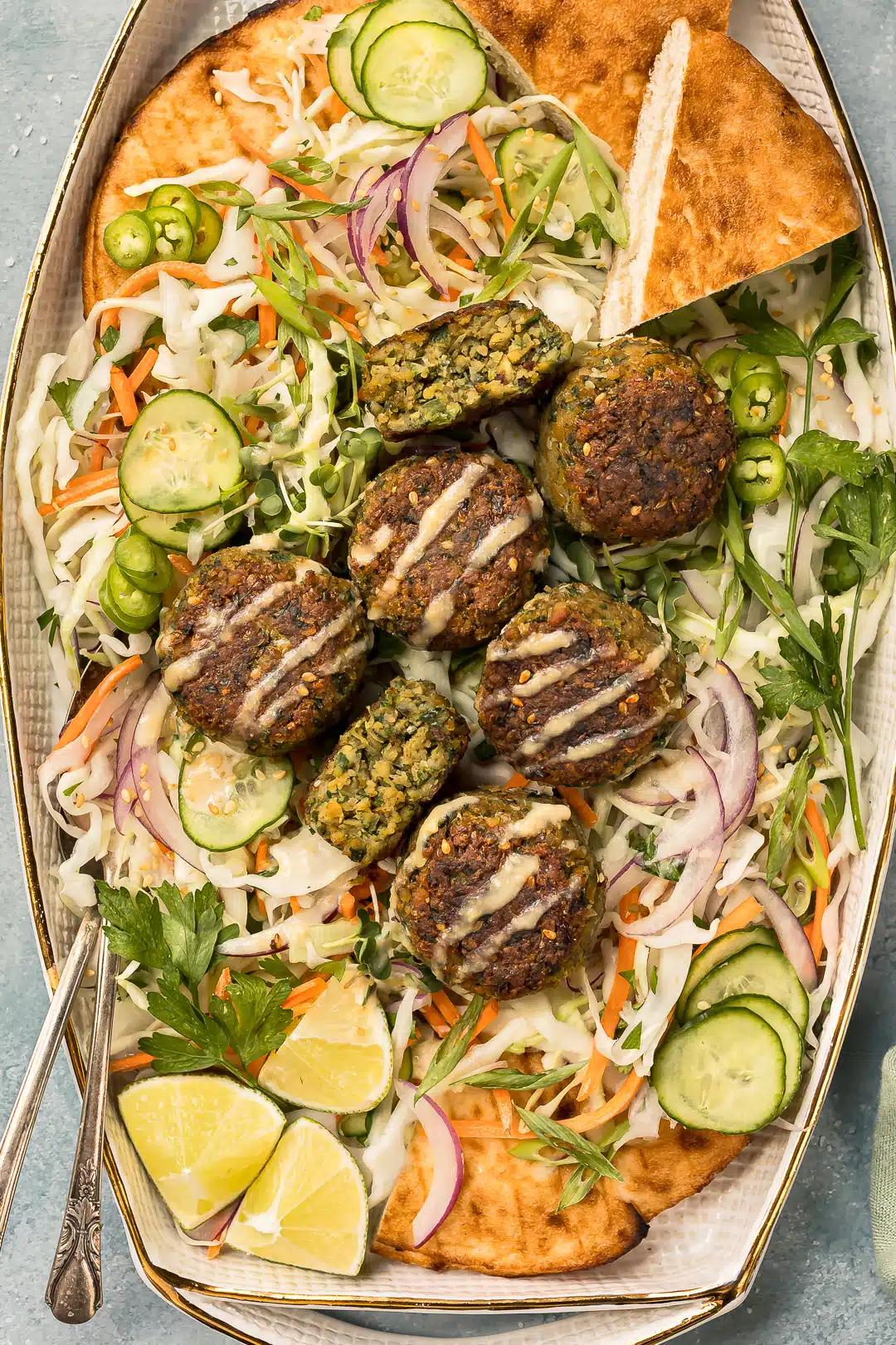 A platter of falafel cakes garnished with fresh cilantro and a side of carrot and ginger salad