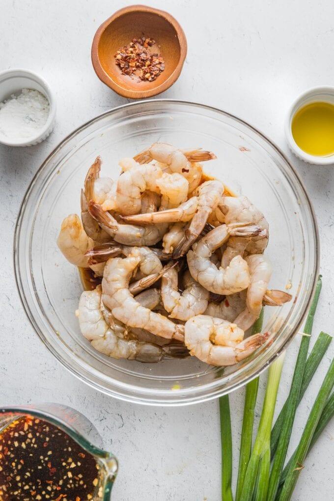 Shrimp marinating in a honey garlic sauce in a glass bowl
