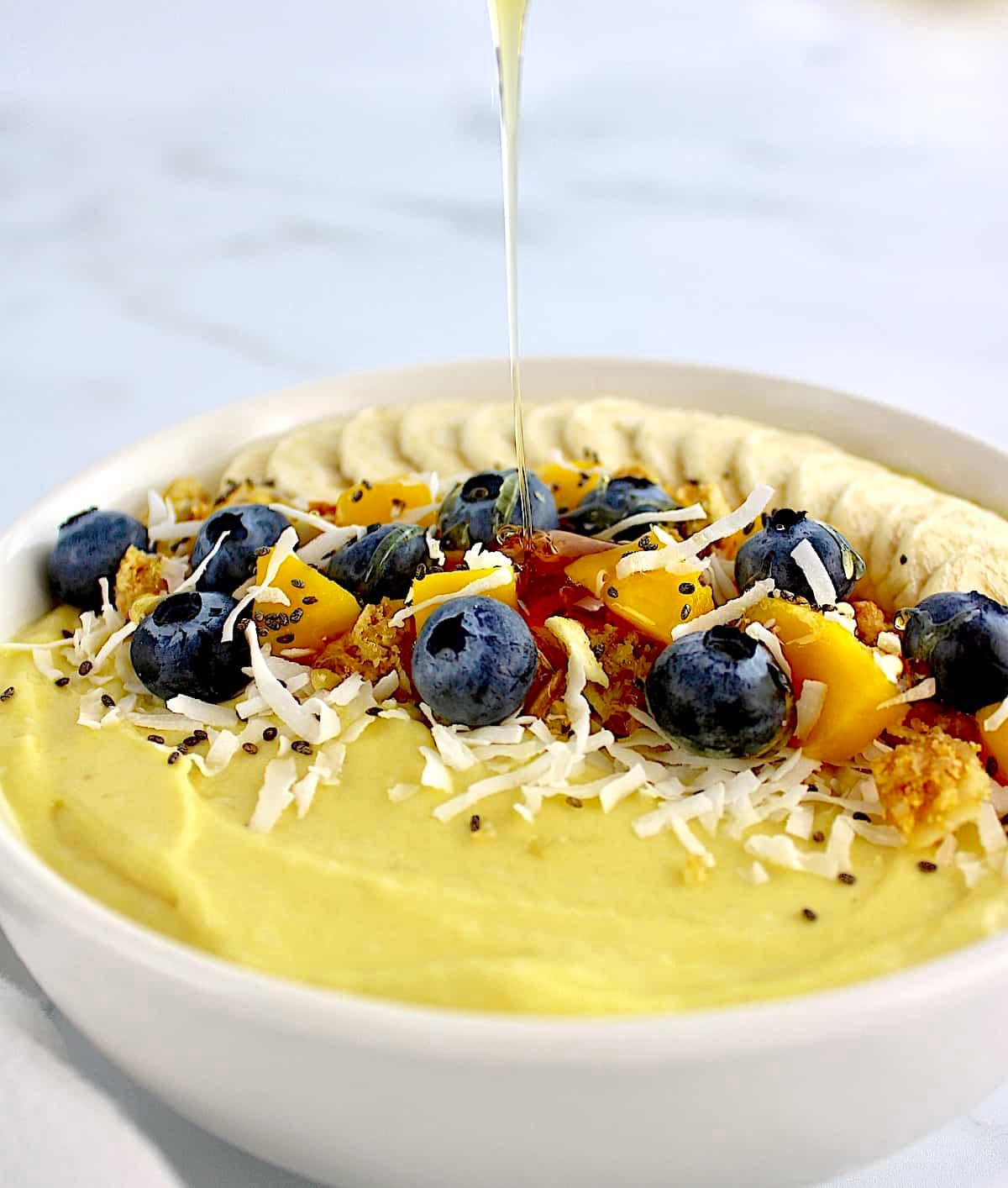 A bowl of creamy coconut yogurt topped with fresh mango and a sprinkle of nutmeg