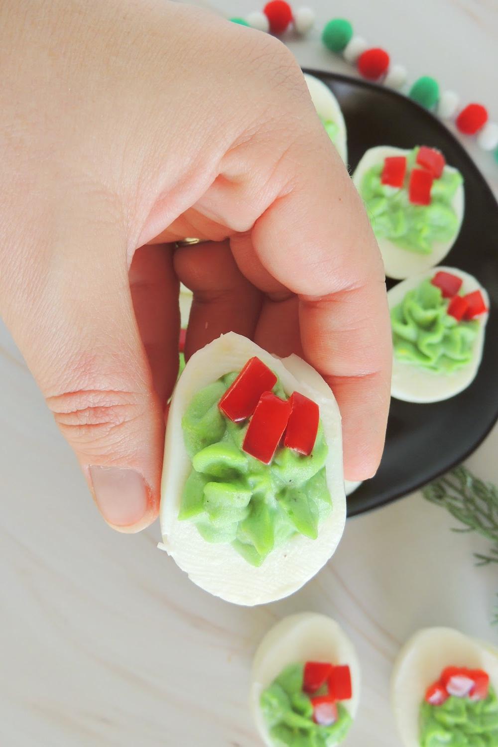 A close-up shot of hands preparing Christmas deviled eggs