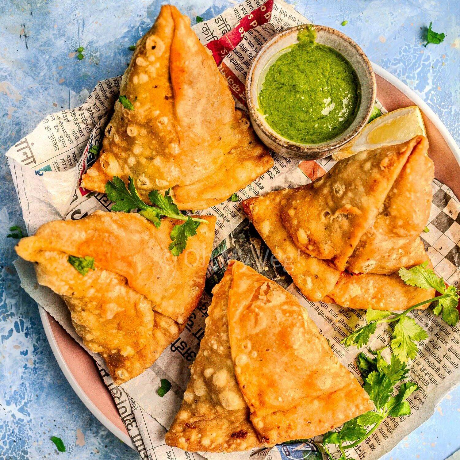 Close-up shot of golden-brown, crispy samosas with a vibrant vegetable filling