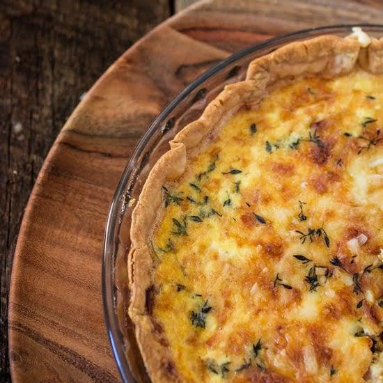 close up shot of golden ham and cheddar quiche bites arranged on a rustic wooden board, dusted with fresh herbs.
