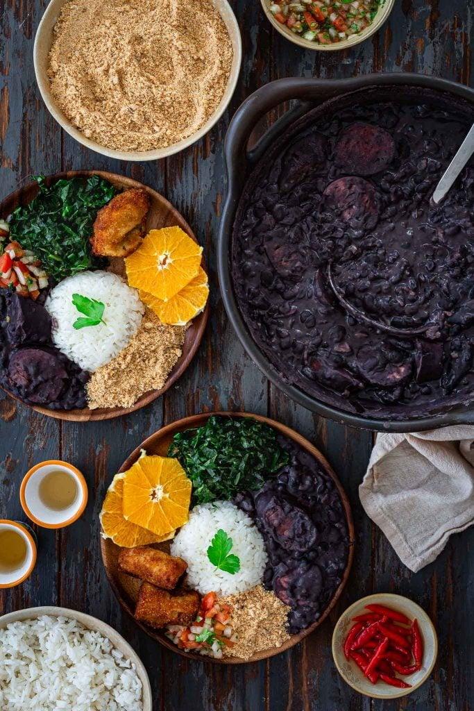 A wide shot of various side dishes served with Feijoada, emphasizing the variety.