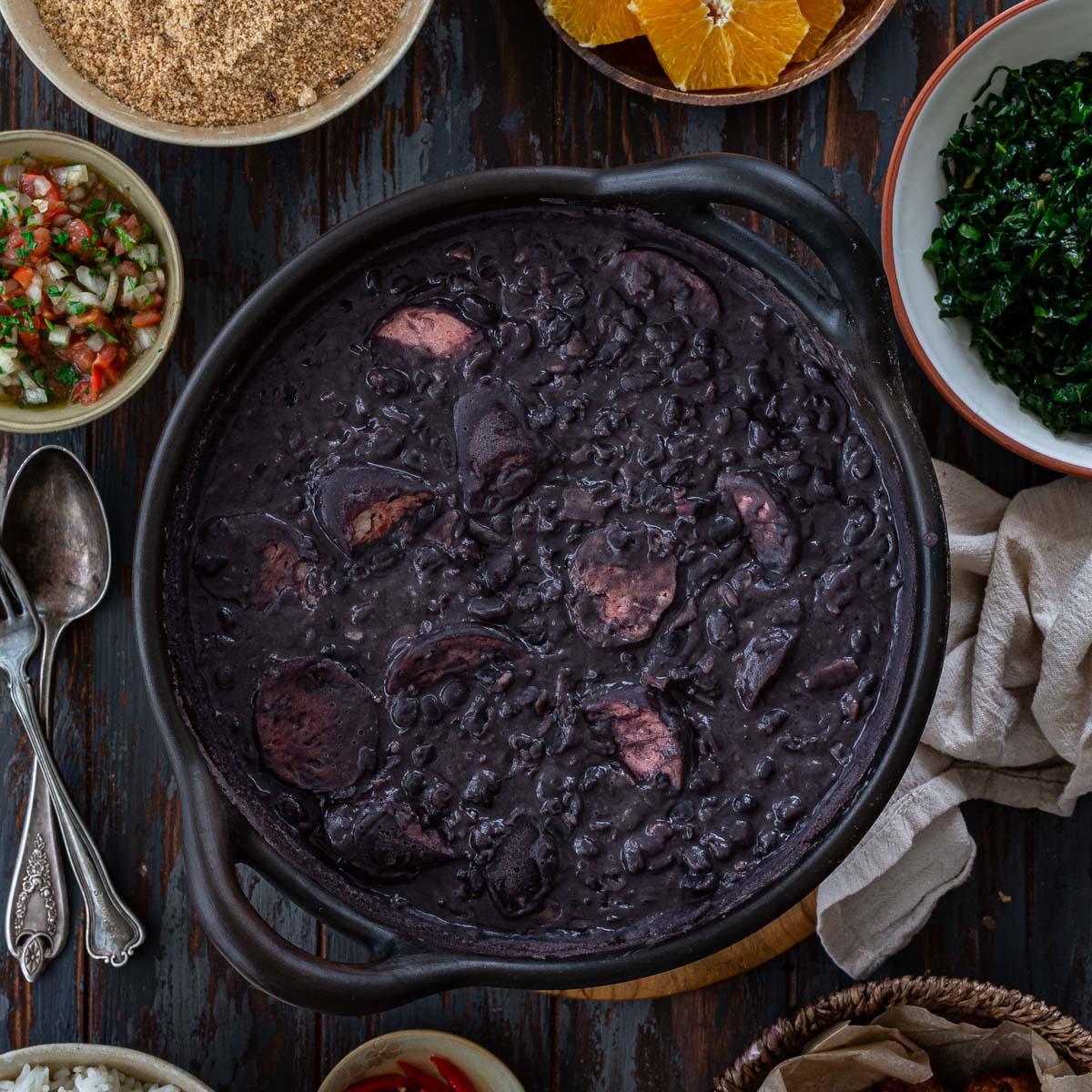 a pot of feijoada simmering on a stovetop, steam rising and spices visible