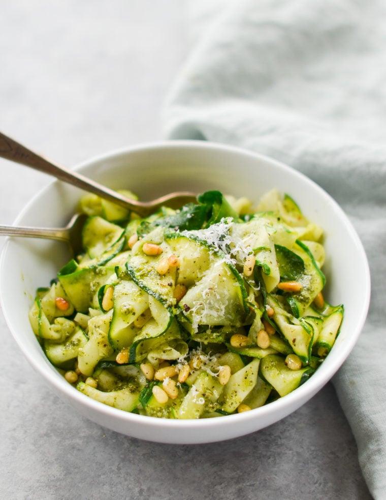 vibrant close-up of zucchini noodles tossed with vibrant green pesto and crunchy pine nuts