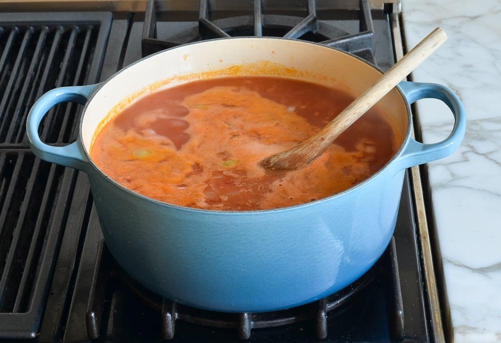 A large pot of tomato soup simmering on a stovetop.