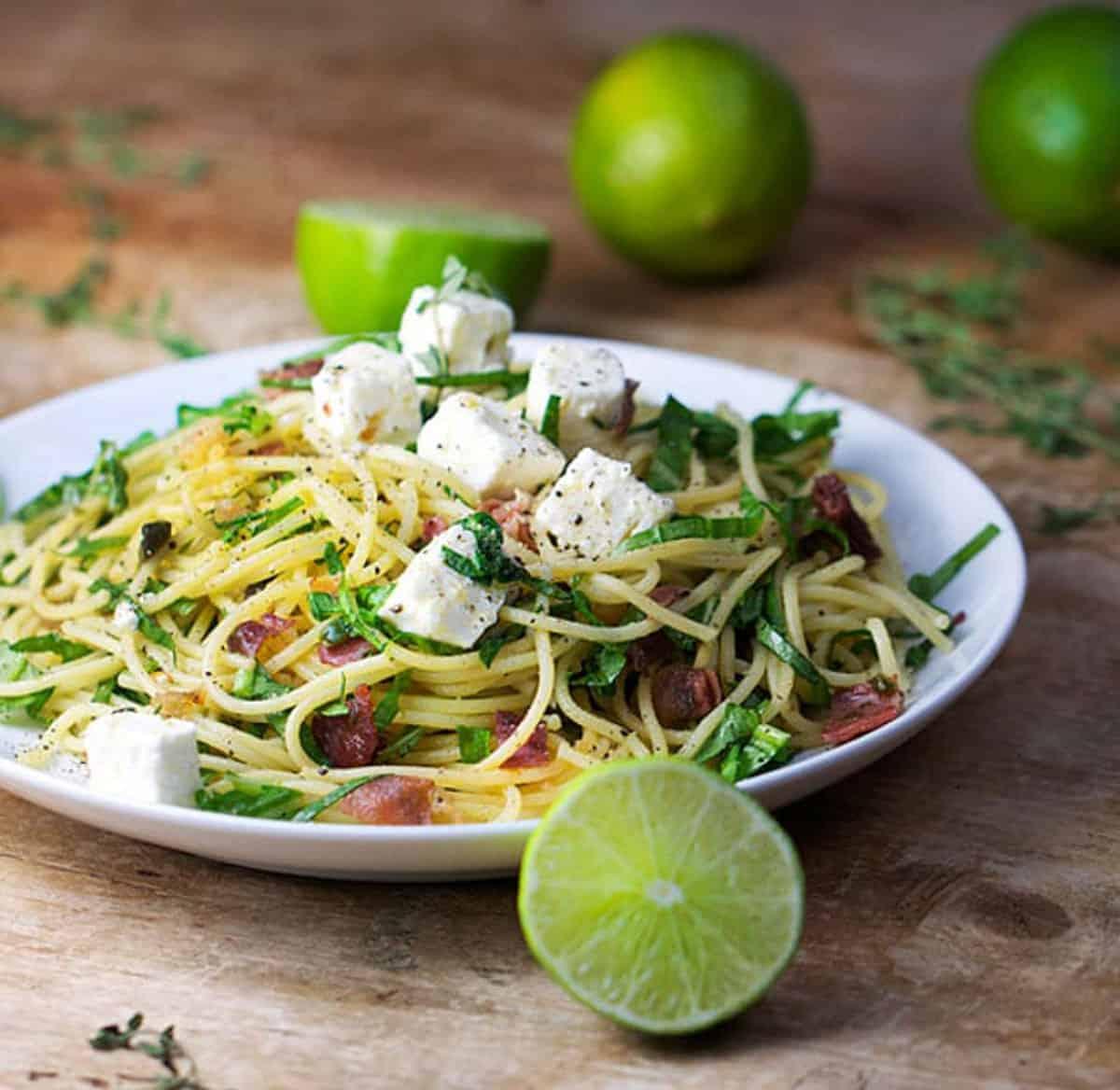 Close up shot of a plate of pasta with prosciutto and arugula