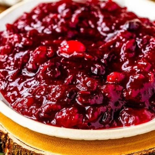 a bowl of roasted cranberries with a spoon, highlighting the texture and color of the cranberries