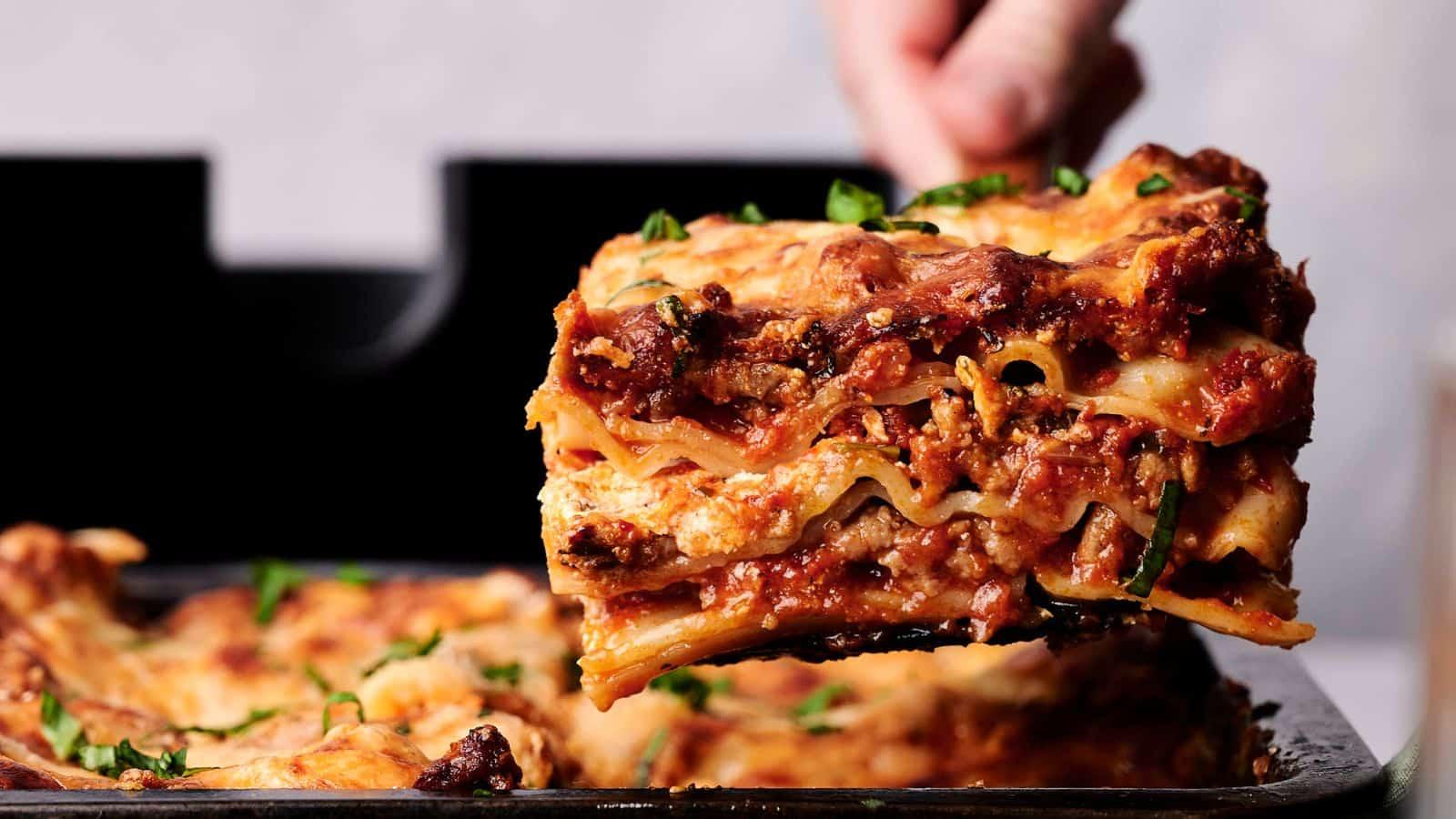 a slice of lasagna being lifted from a baking dish, showcasing the layers