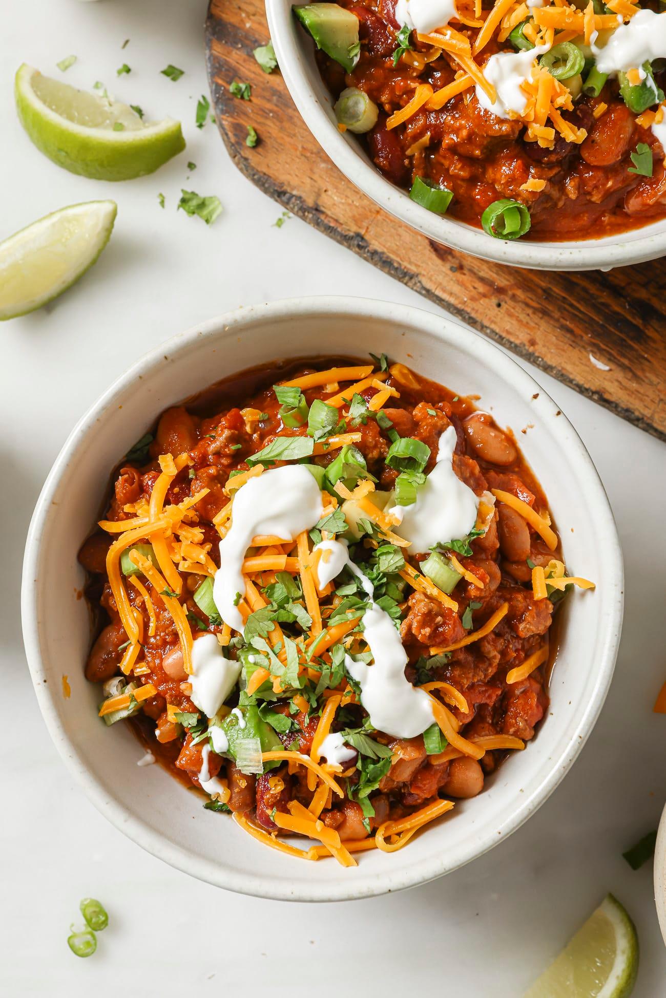A slow cooker filled with hearty kale chili, garnished with cilantro and a dollop of sour cream.