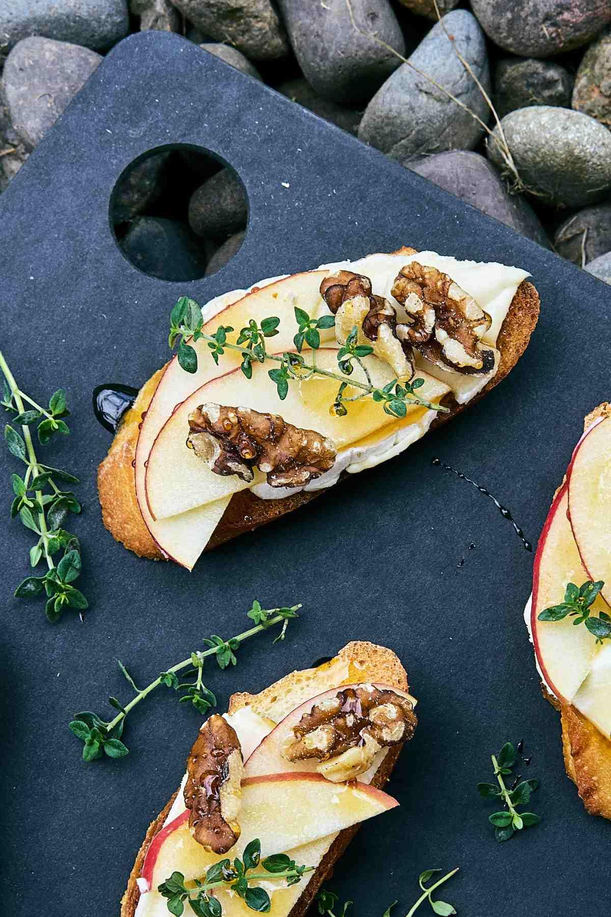 Close-up shot of apple and brie bruschetta on a rustic wooden board