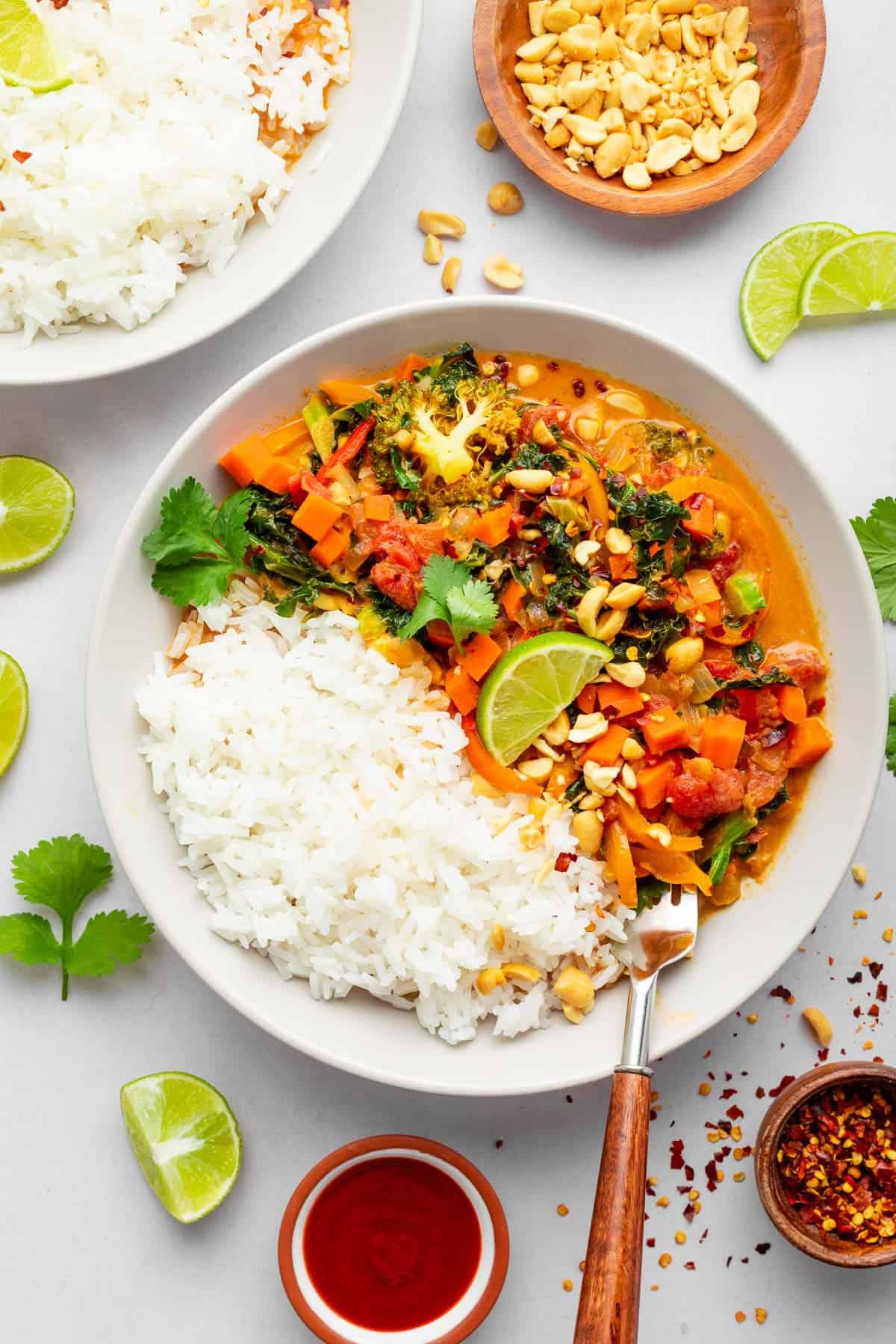 A vibrant and colorful bowl of grilled vegetable curry, garnished with fresh cilantro and a squeeze of lime.