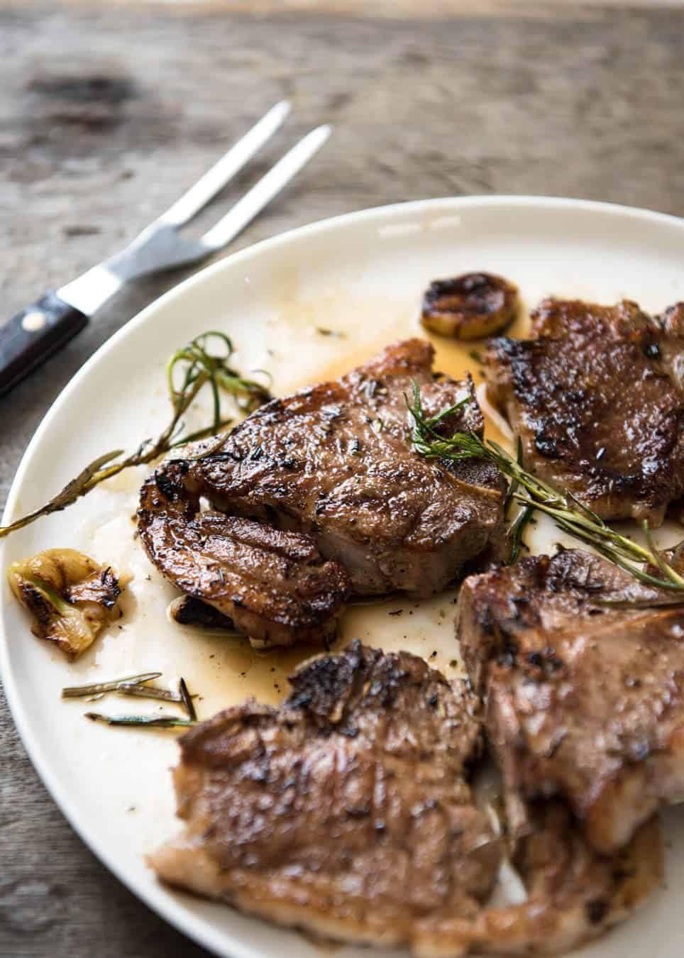 A plate of grilled lamb chops garnished with rosemary and thyme