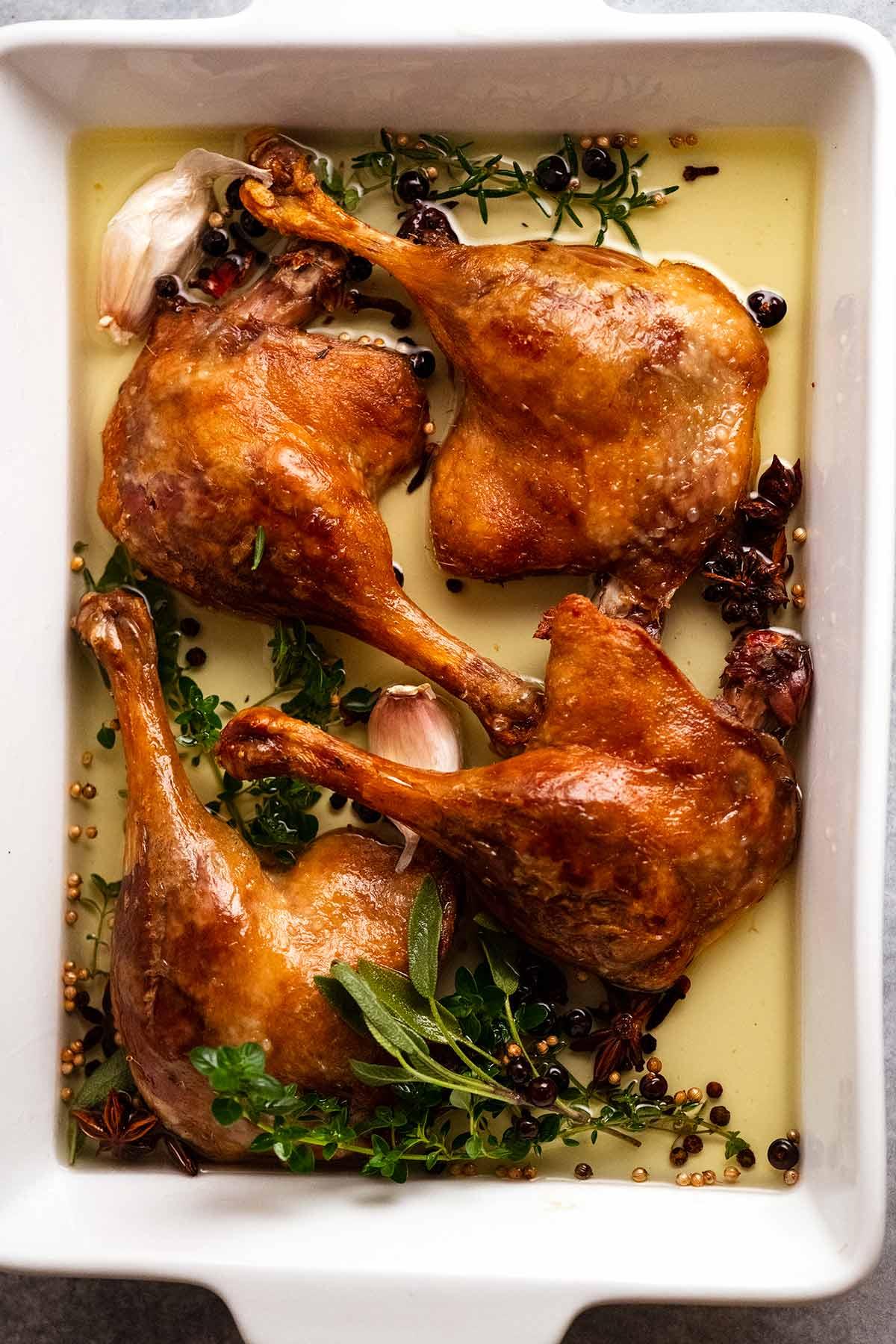 Close-up shot of duck confit legs in a glass jar, submerged in duck fat