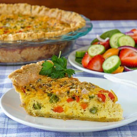 Close-up shot of a slice of grilled vegetable quiche, showcasing the vibrant colors of the vegetables and the flaky crust