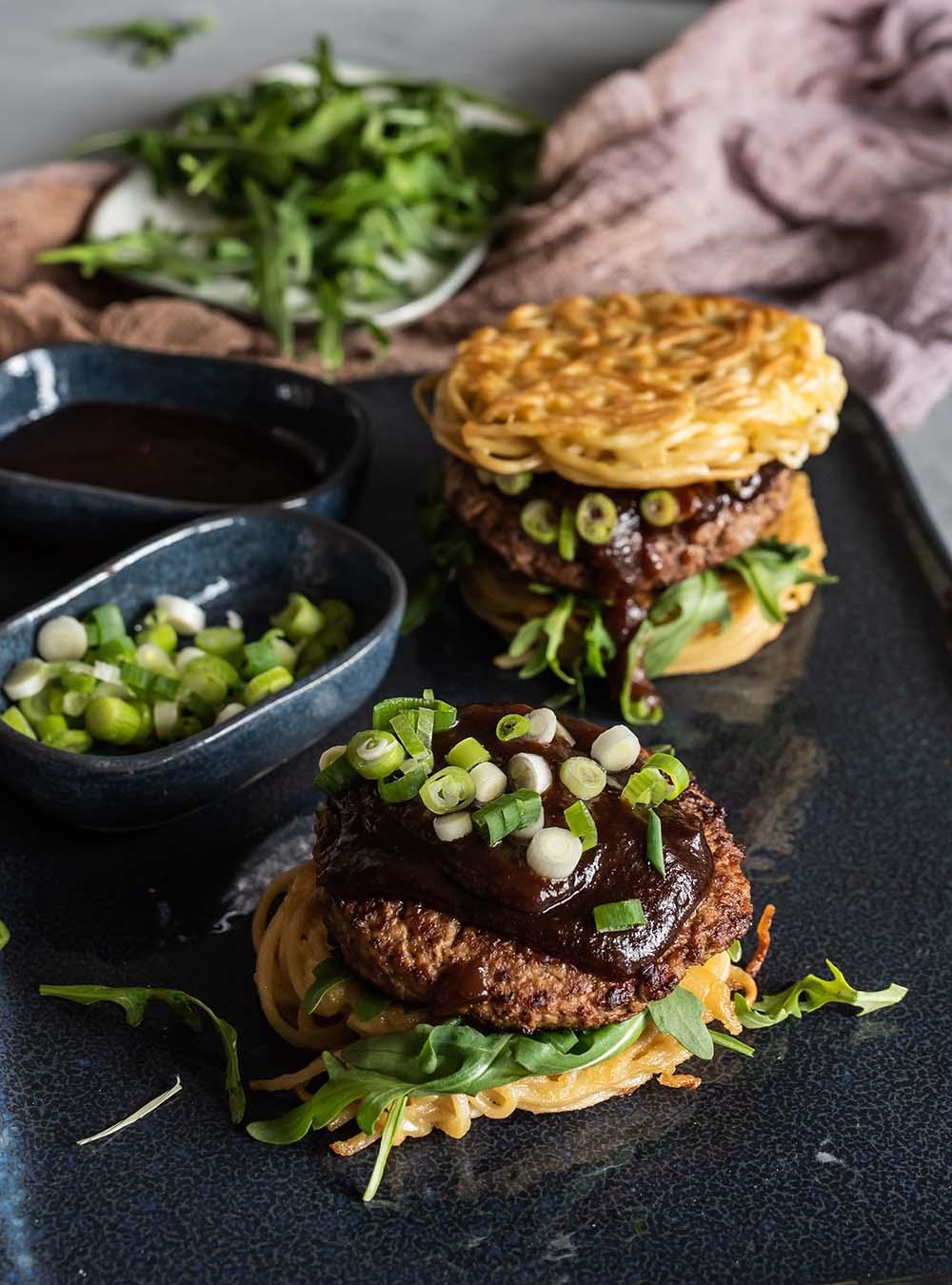 Close-up shot of a ramen burger with grilled halloumi and vibrant green mint chutney, garnished with fresh mint sprigs