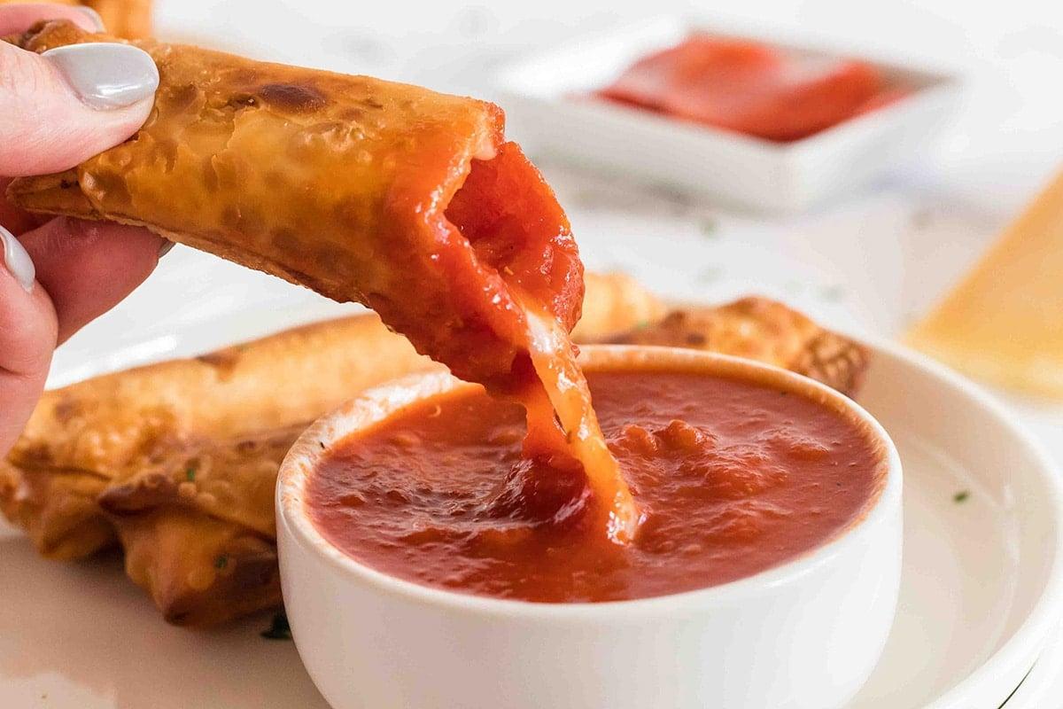 Close-up shot of golden-brown sheet pan pizza rolls with marinara sauce for dipping