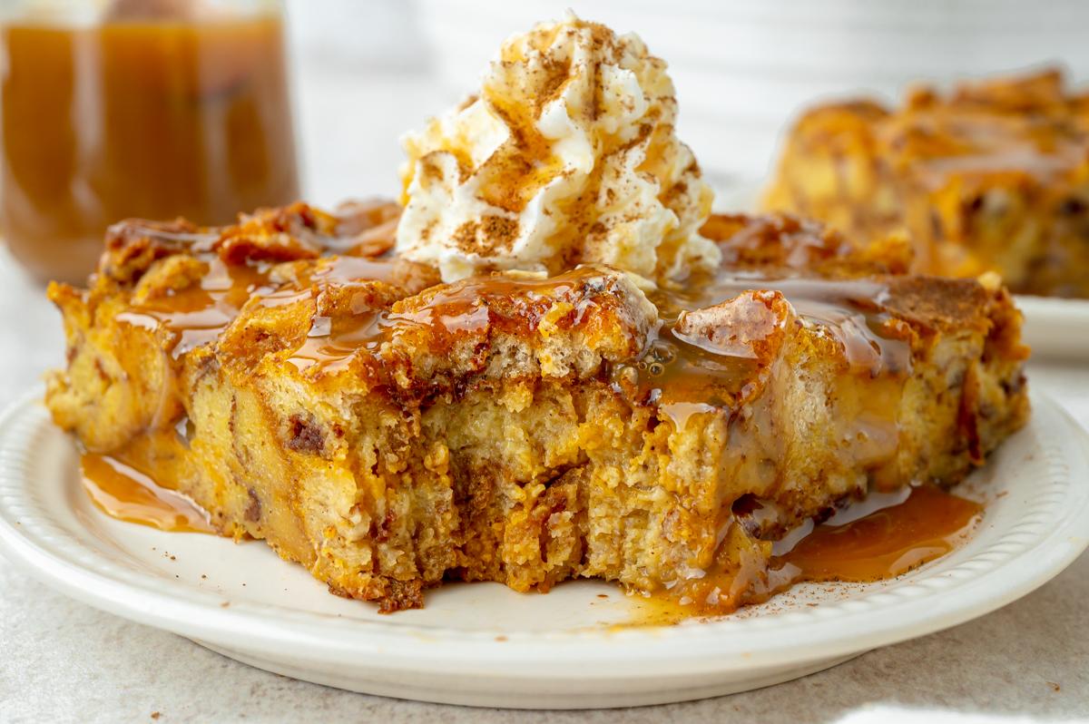 A close-up shot of a slice of pumpkin bread pudding with caramel sauce