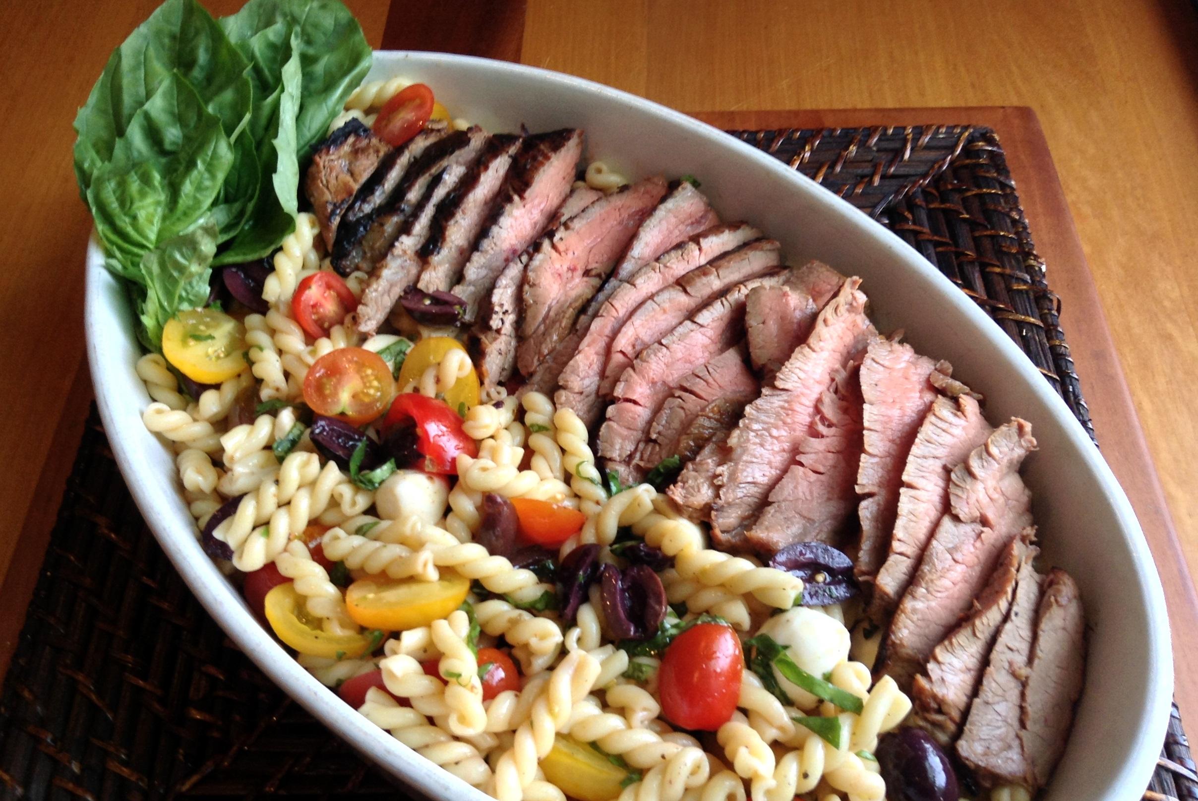 Person preparing the steak and macaroni salad