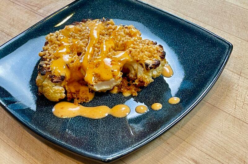 Close-up of crispy fried cauliflower steaks arranged on a platter with spicy mayo for dipping