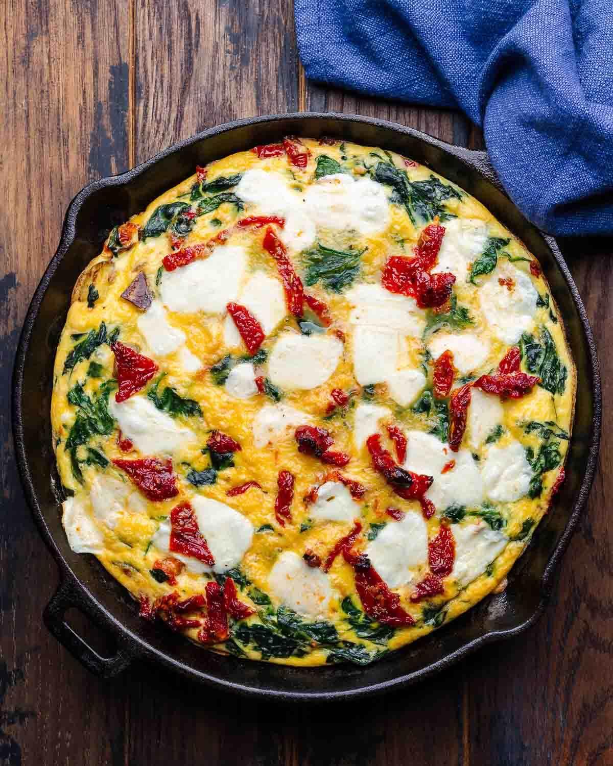 overhead shot of a freshly baked sun-dried tomato and mozzarella frittata in a skillet