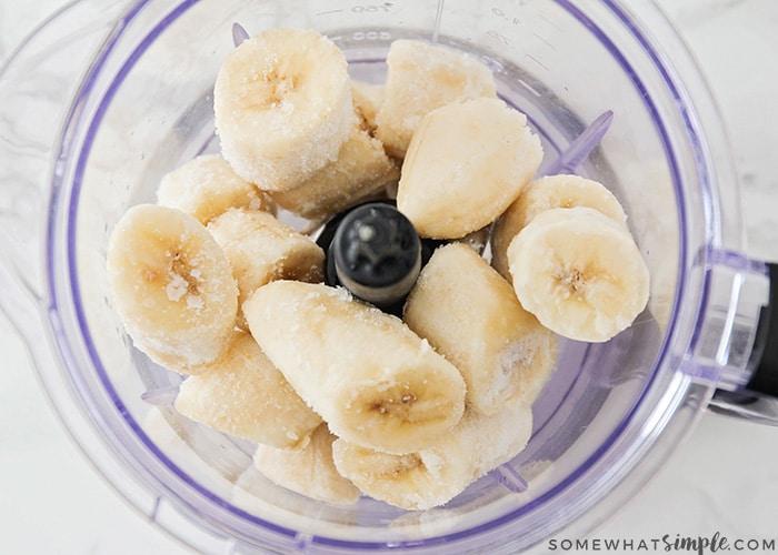 A person adding frozen banana slices into a blender