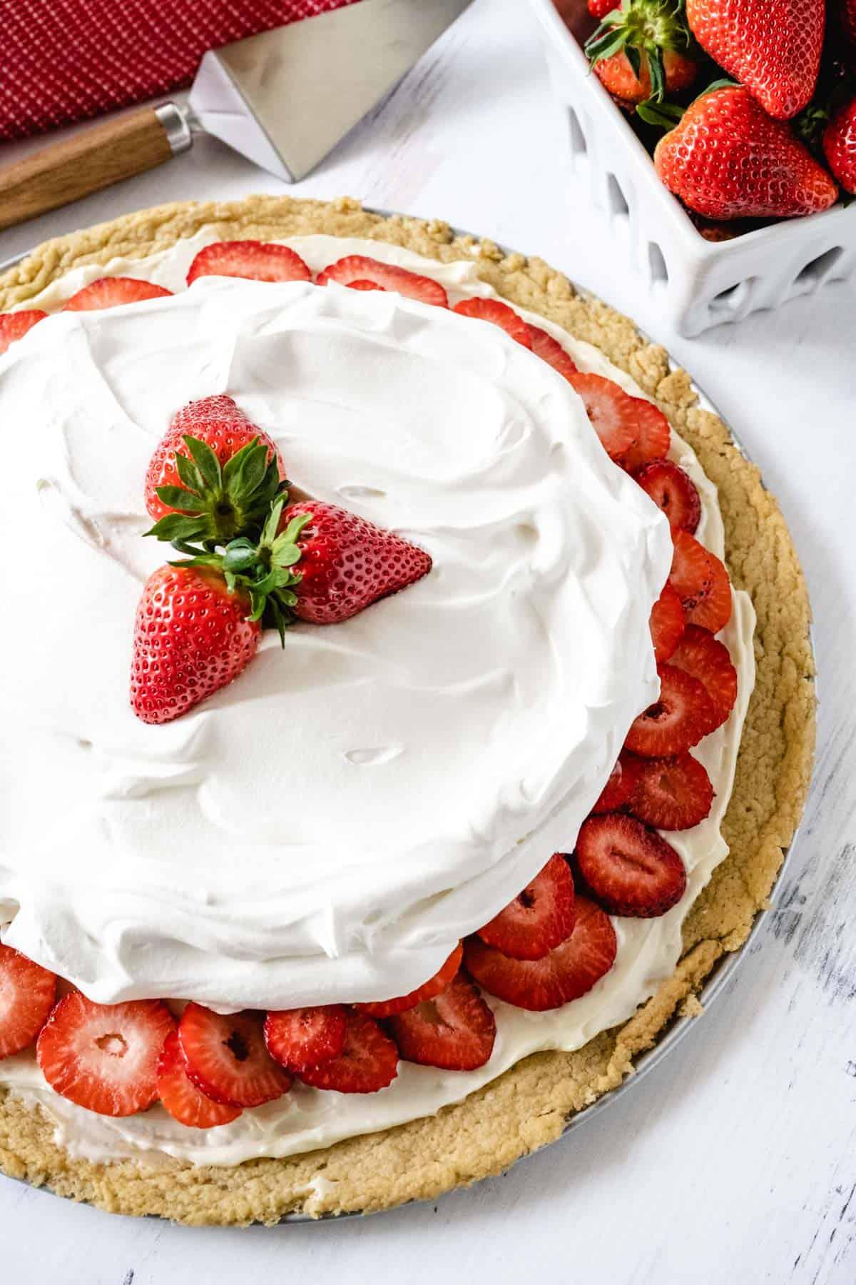 Close up shot of a Strawberry Shortcake Pizza, showing the layers of crust, strawberries and whipped cream.