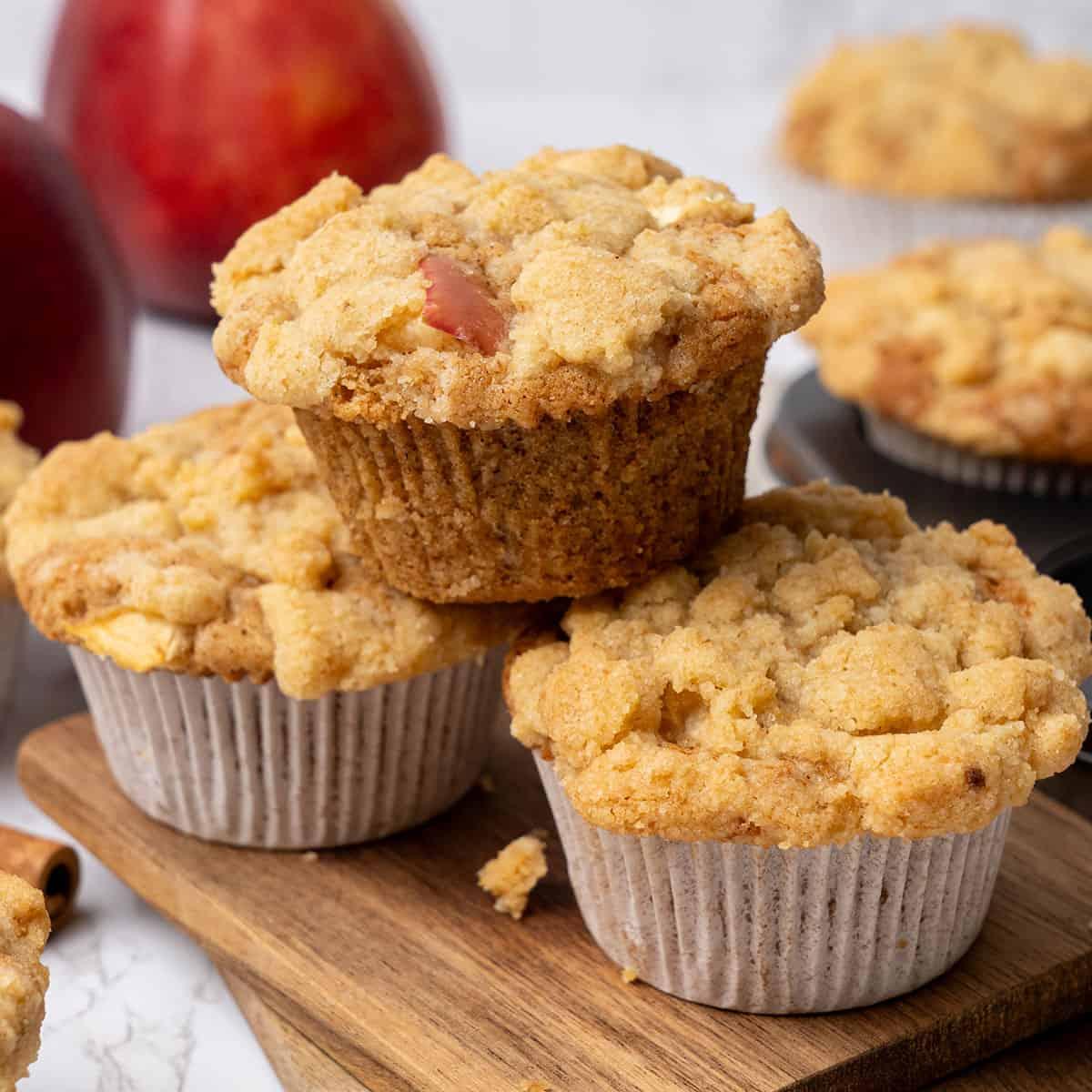 A plate of apple crumble muffins on a rustic wooden table, garnished with fresh apples slices