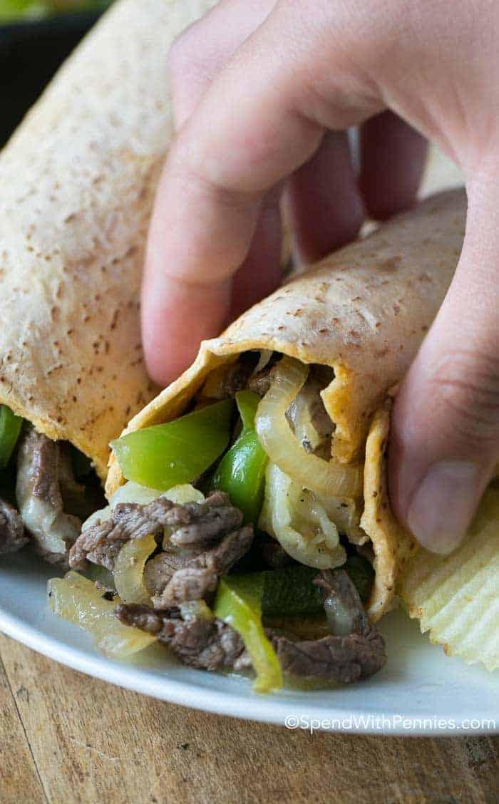 A person enjoying a steak and cheese wrap