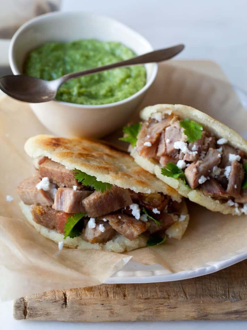 Overhead view of assembled smoked brisket arepas with guasacaca, garnished with cilantro