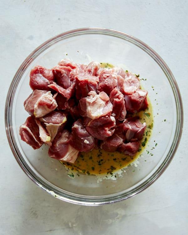 A bowl of marinade with lamb cubes soaking