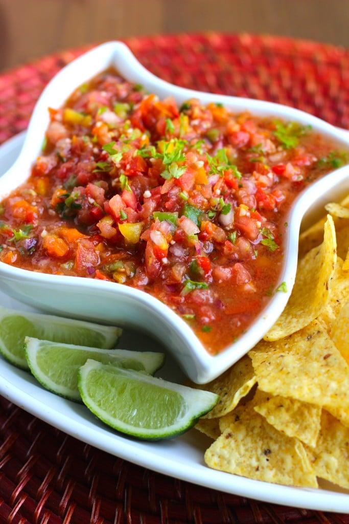 A bowl of fresh lime-cilantro salsa, garnished with lime wedges and cilantro sprigs.