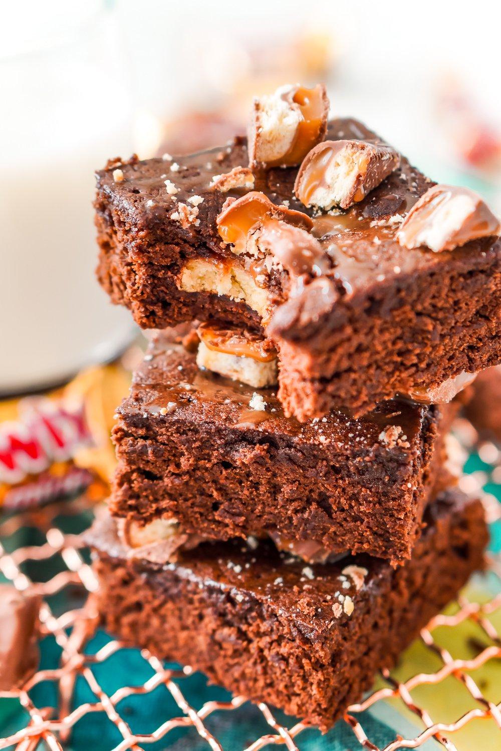 Close-up shot of a pan of warm Twix brownies, showing caramel swirls and chocolate chunks