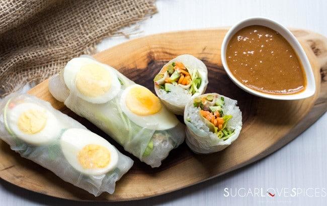a serving platter of freshly made boiled egg and spring rolls with a dipping sauce