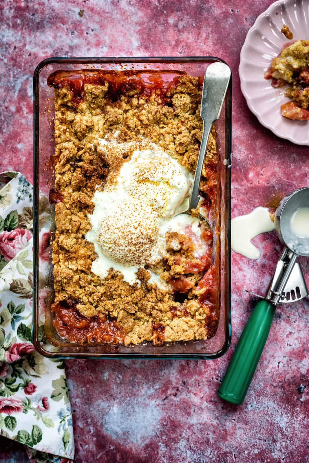 Close-up shot of a rustic apple crisp with plums, showing the texture of the topping and the juicy fruit underneath.