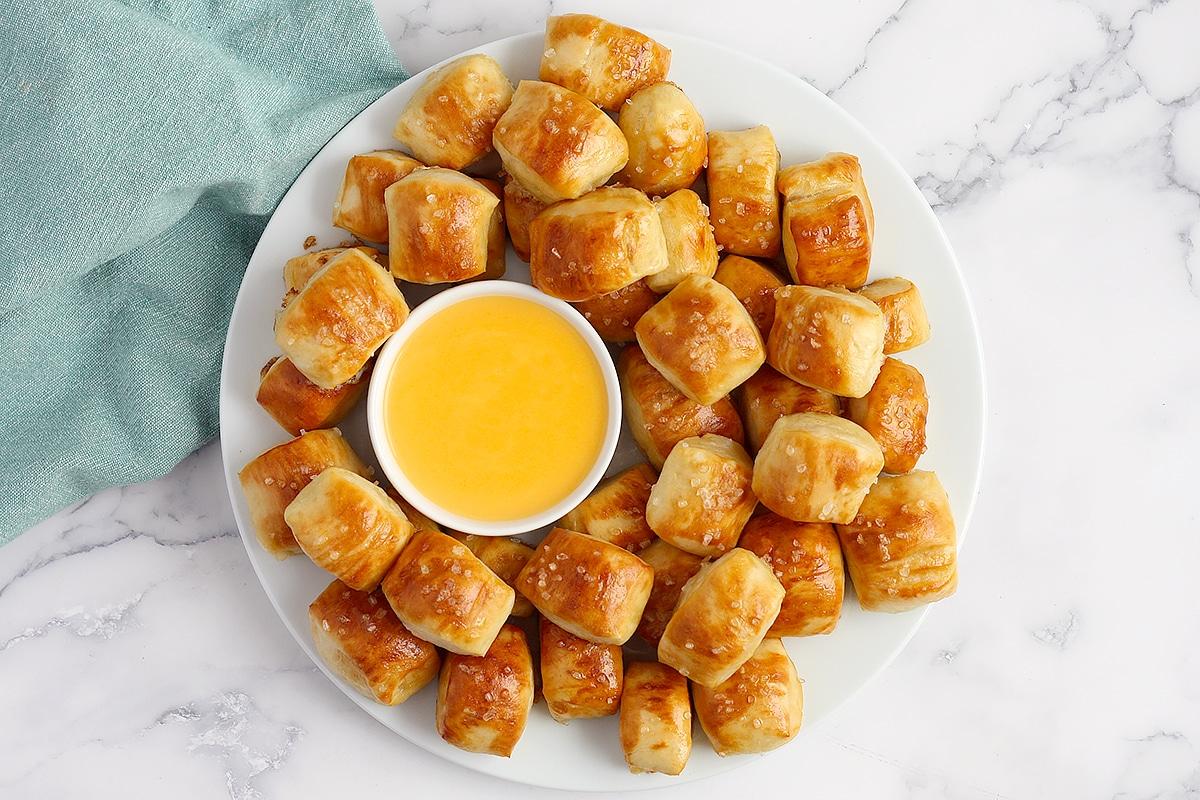 A plate of golden brown pretzel bites with a side of rich caramel dip