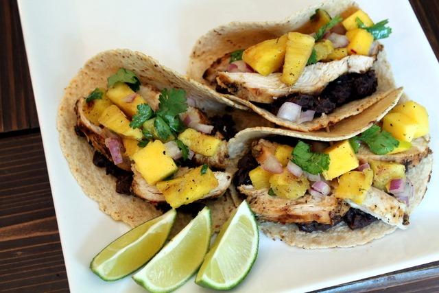 A person enjoying a grilled pineapple chicken taco on a beach in Mexico