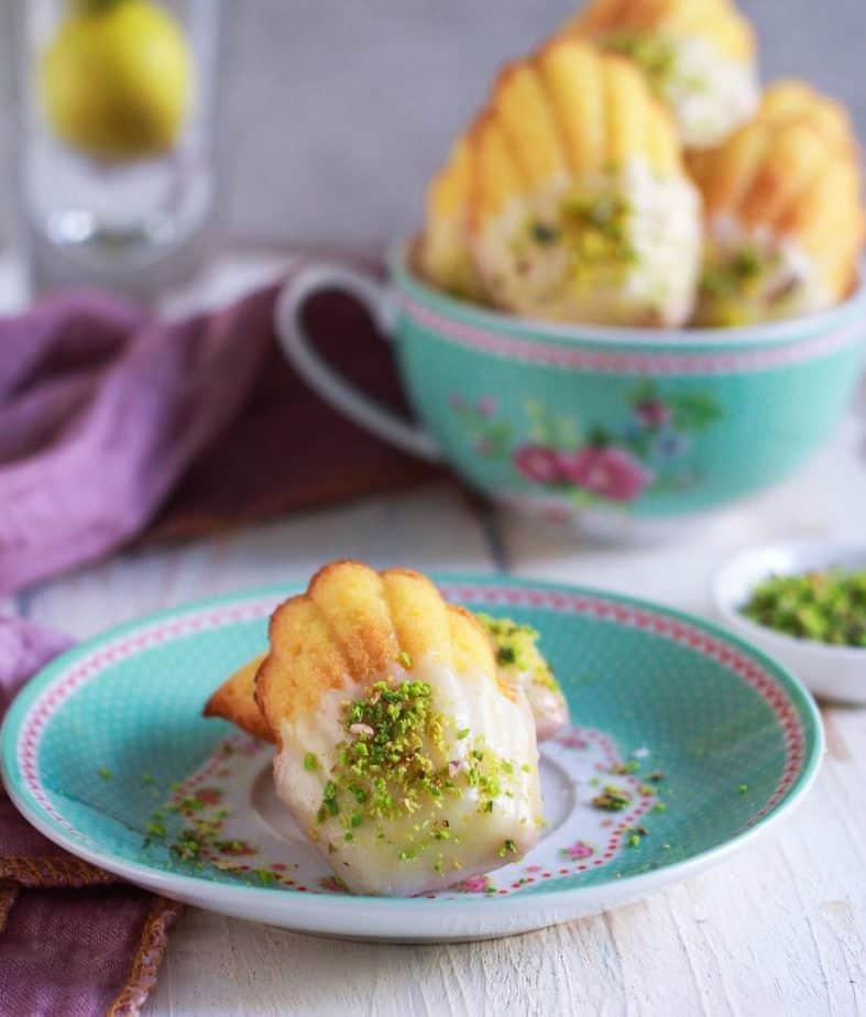 A plate of lemon and pistachio madeleines, garnished with powdered sugar