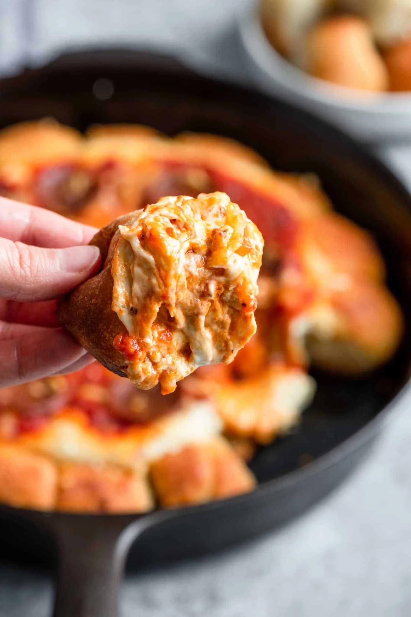 Close-up shot of mini pizzas in a cast iron skillet, cheese bubbling and golden brown