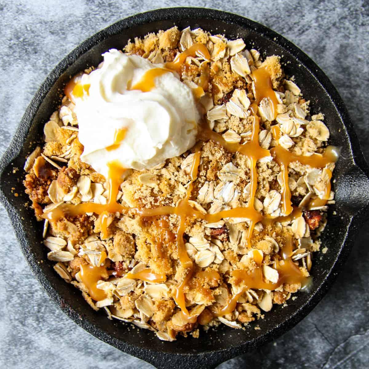 golden brown apple crisp in a baking dish, garnished with fresh thyme sprigs and a drizzle of honey