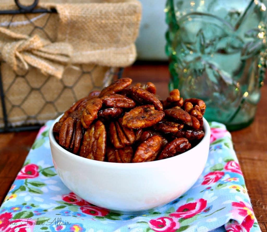 A rustic wooden bowl overflowing with maple-glazed candied pecans