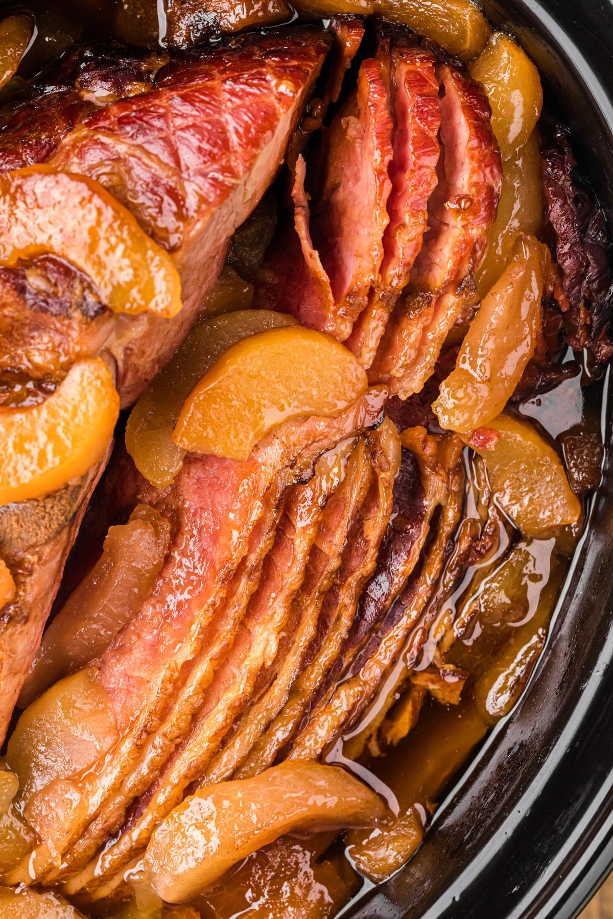 close-up shot of a ham soaking in an apple-sage brine in a large pot