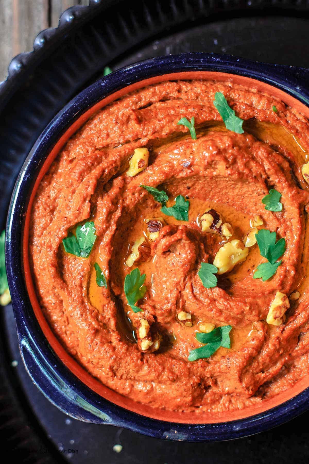 A person enjoying a large bowl of Roasted Red Pepper & Walnut Fattoush outside on a sunny day