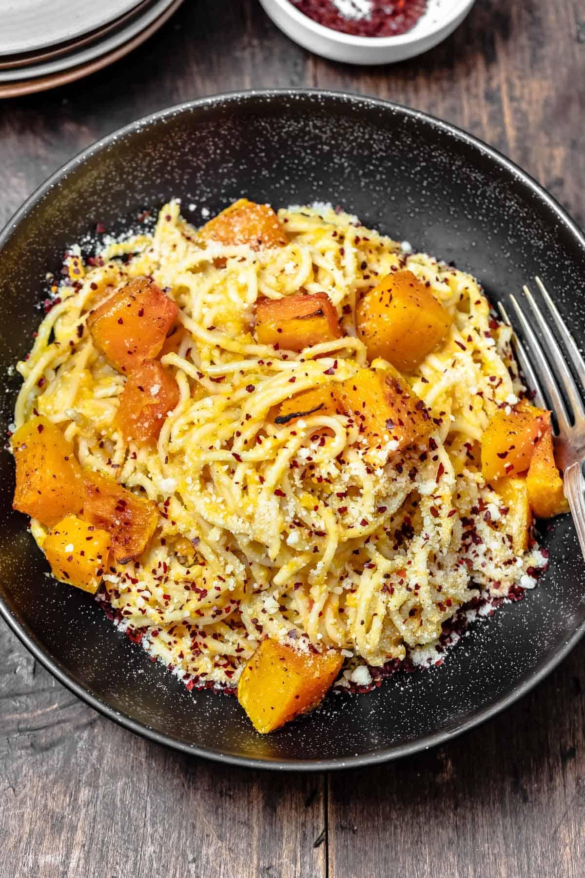 A table set for dinner with a bowl of butternut squash pasta in the center