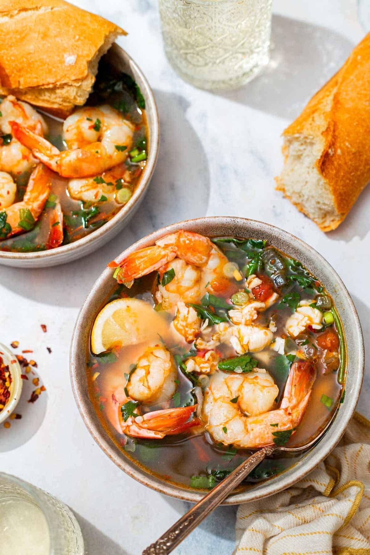 Overhead shot of a table set for dinner with a bowl of shrimp stew in the center