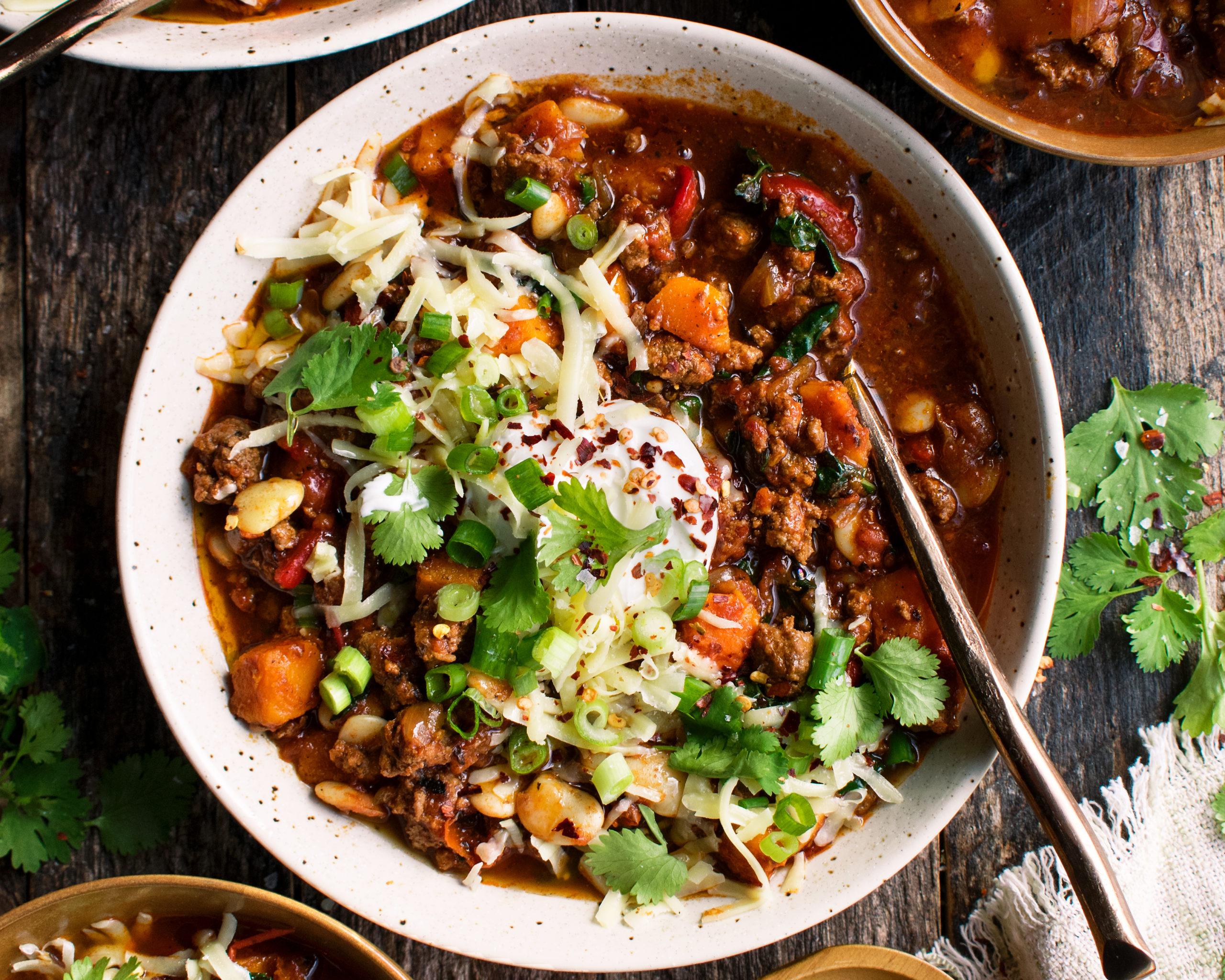 A hearty bowl of spicy lamb chili topped with fresh cilantro and a side of warm cornbread