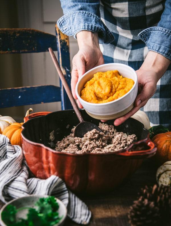 Person ladling pumpkin chili into a bowl