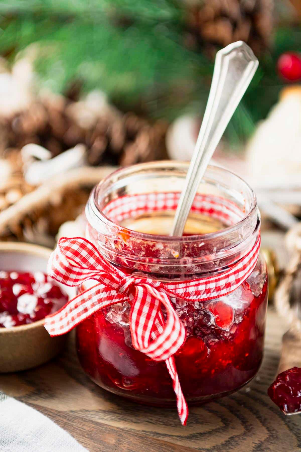 A jar of homemade lingonberry jam with a spoon resting inside